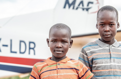 Two boys are among the crowd to greet the MAF plane at an airstrip in the Karamoja region of Uganda, after a long runway closure during the Covid pandemic